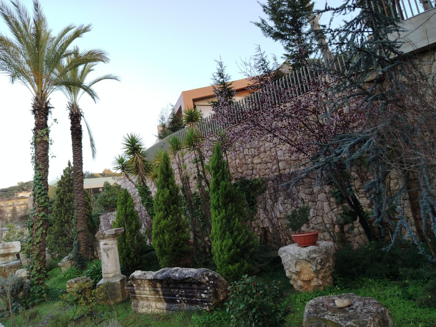 Villa Chaaya garden with palms, cypress and stone fragments